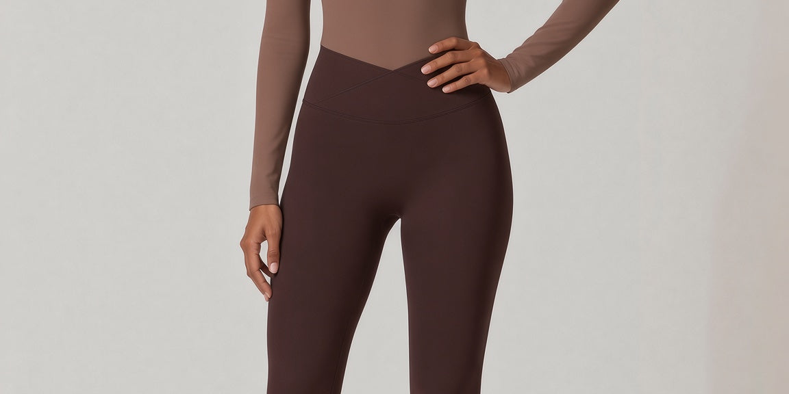 A woman modeling a two-piece activewear set consisting of a long-sleeve scoop-neck bodysuit in taupe with a scalloped neckline and matching dark brown leggings, shot against a neutral light gray studio background.